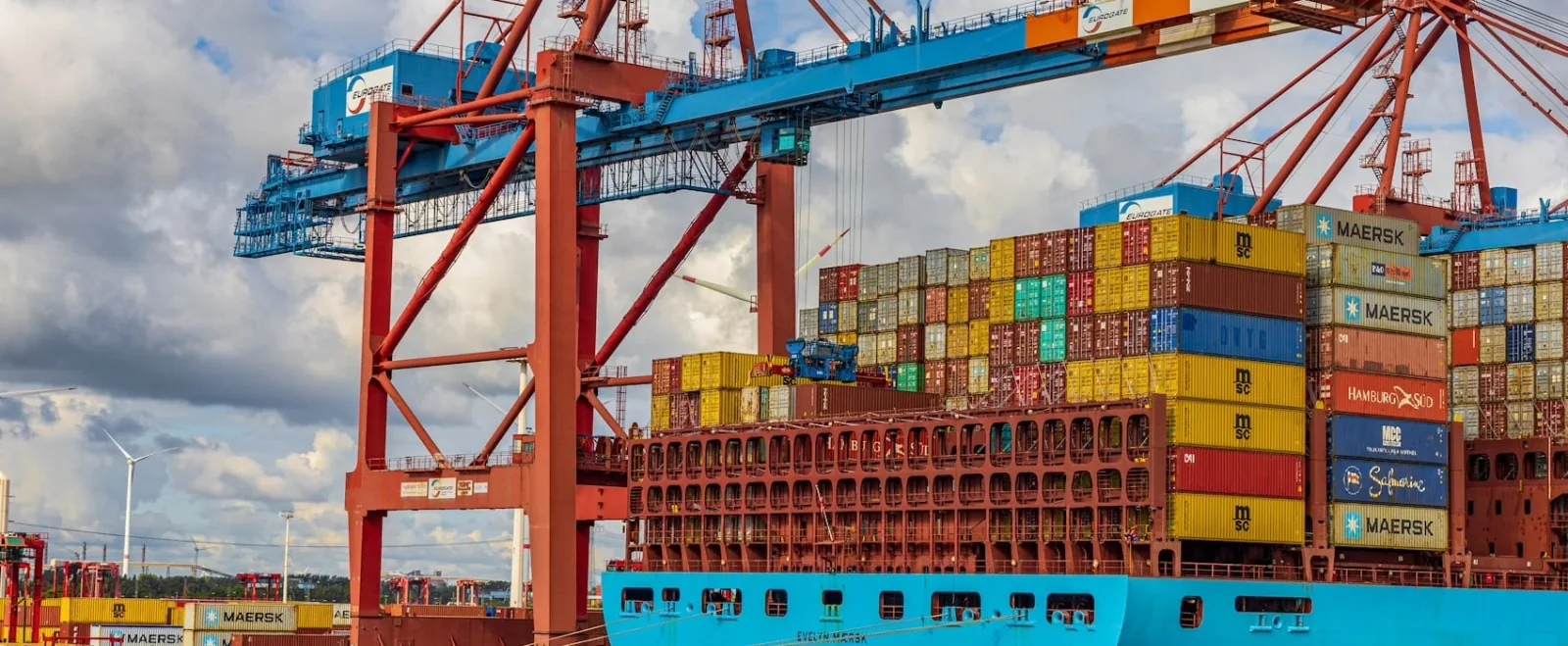 Ocean freight container ship alongside port cranes